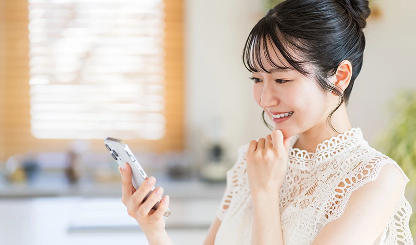 スマートフォンで自宅のスマートデバイスを操作する女性