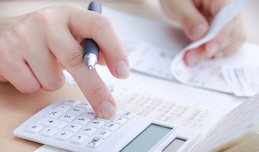 電卓とペンを使って家計を計算している様子